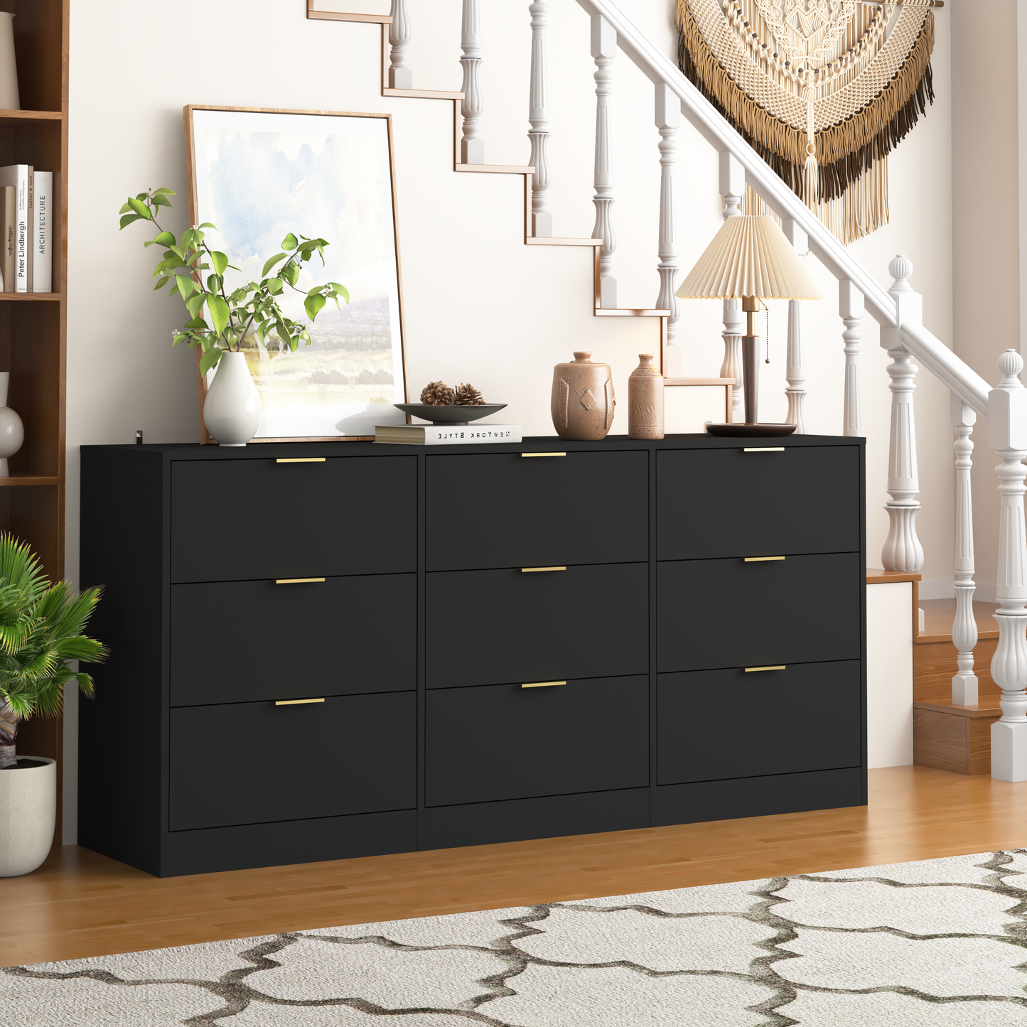 Black dresser with gold handles in a room with a staircase and decor items.