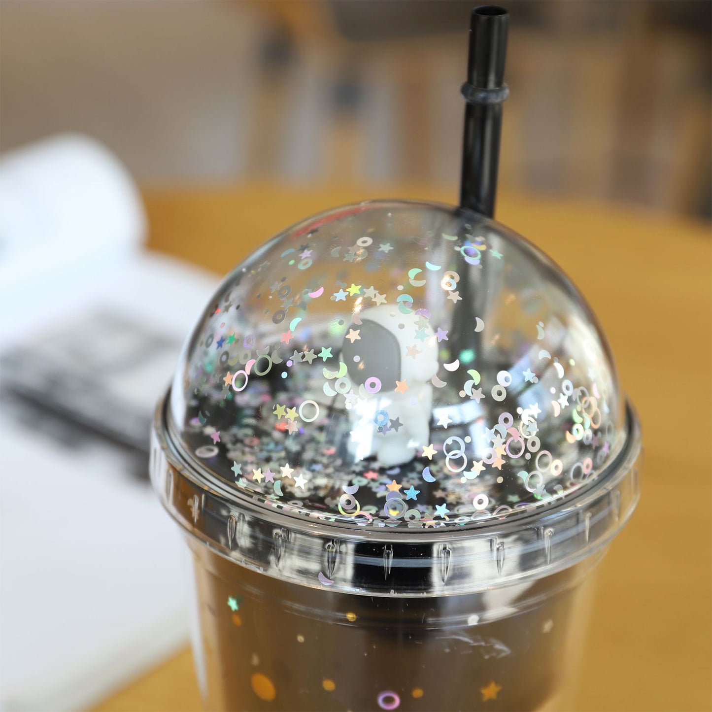 Clear cup with glittery lid and straw on a blurred background