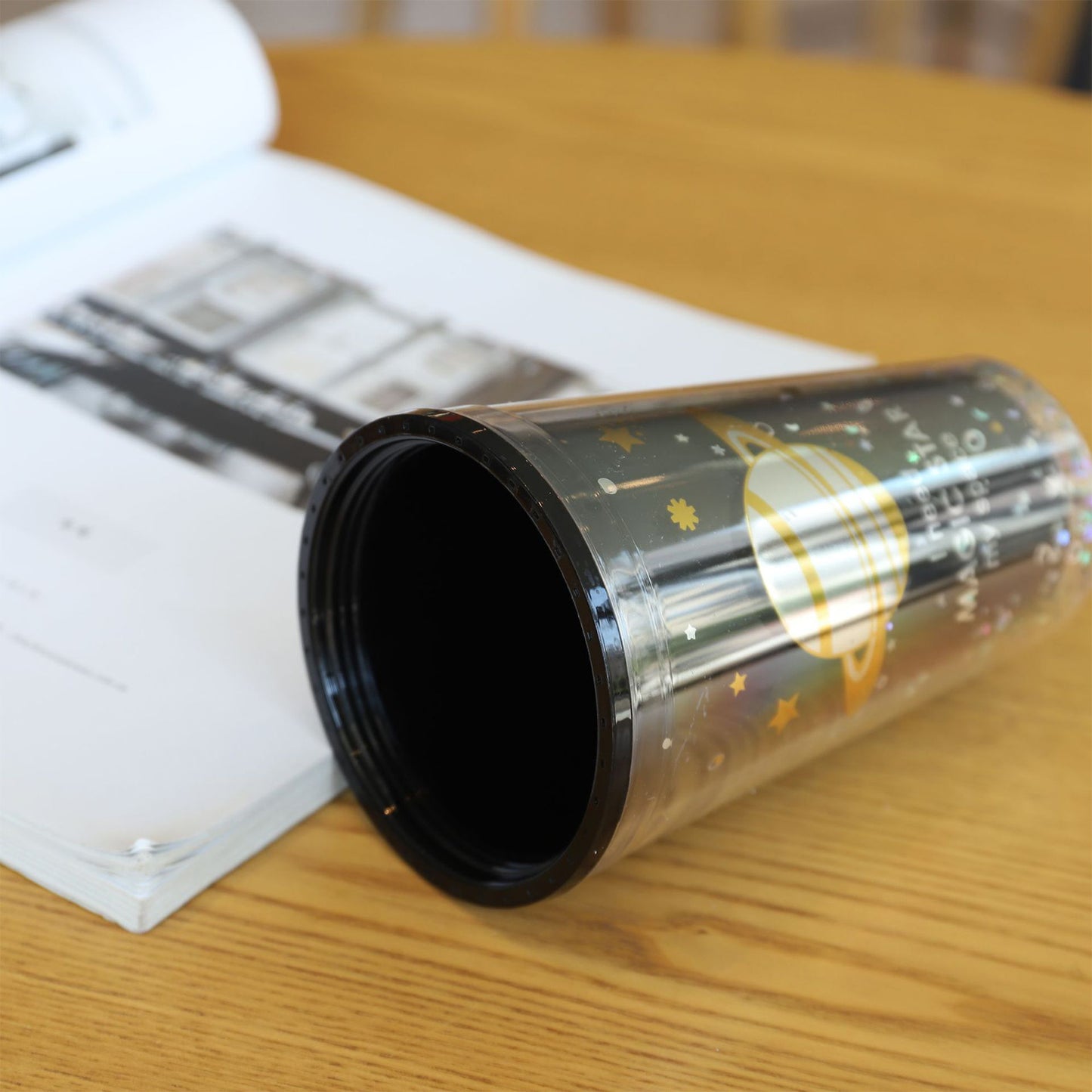 Clear cylindrical container with black interior on a wooden surface