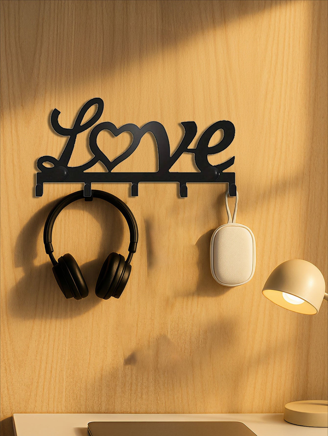 Decorative wall hook shaped like the word 'love' with headphones and a speaker attached on a wooden wall.