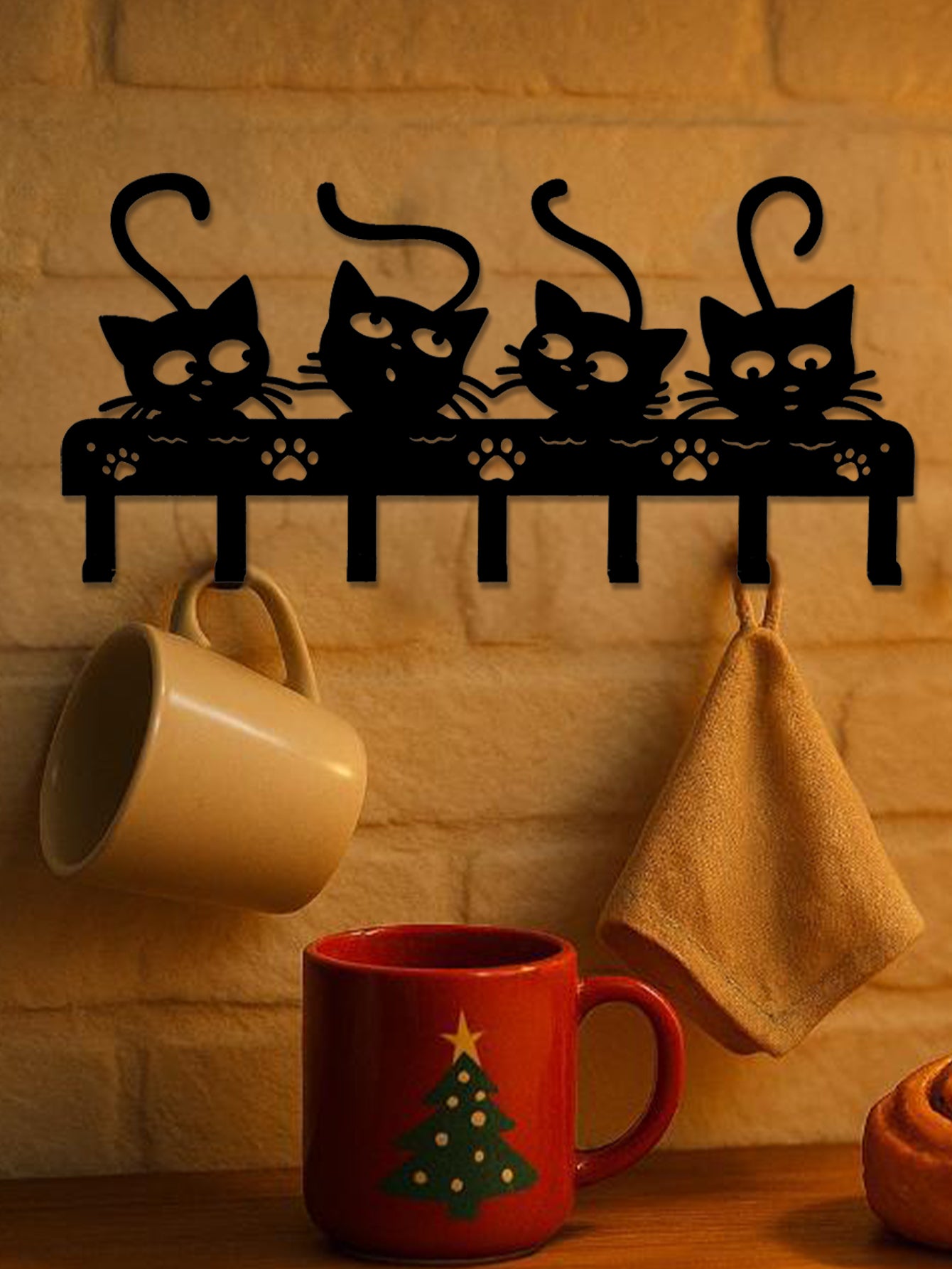 Decorative wall hook with cat design on a wall with mugs and a towel hanging.