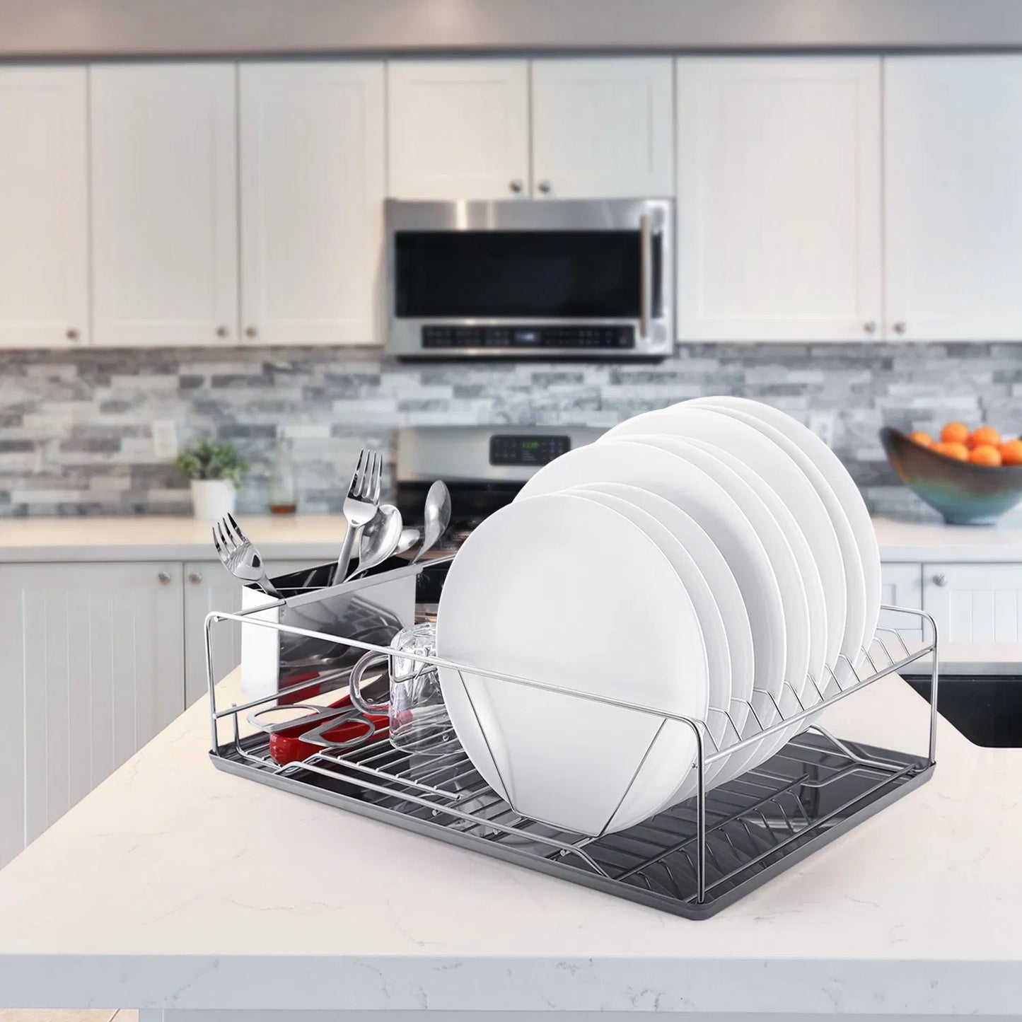 Dish drying rack with white plates and utensils on a kitchen counter.