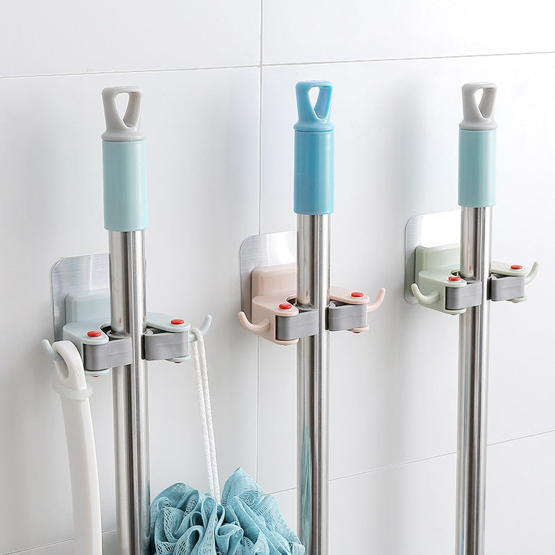 Three mops with attachments mounted on a tiled wall.
