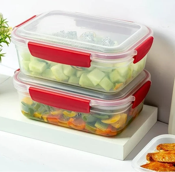Two stacked food storage containers with red lids on a white surface.