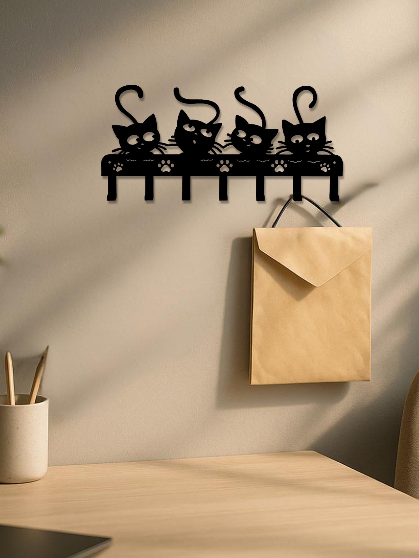 Wall-mounted cat-shaped hook rack with a beige envelope attached on a neutral wall.