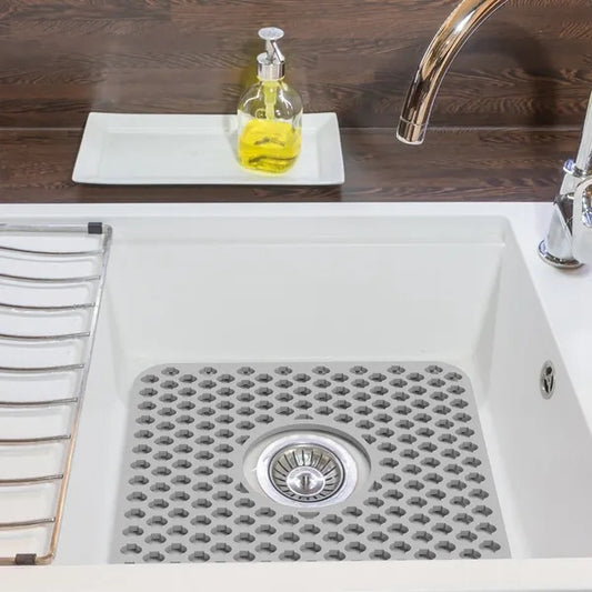 White kitchen sink with drain cover, soap dispenser, and faucet on a wooden countertop.